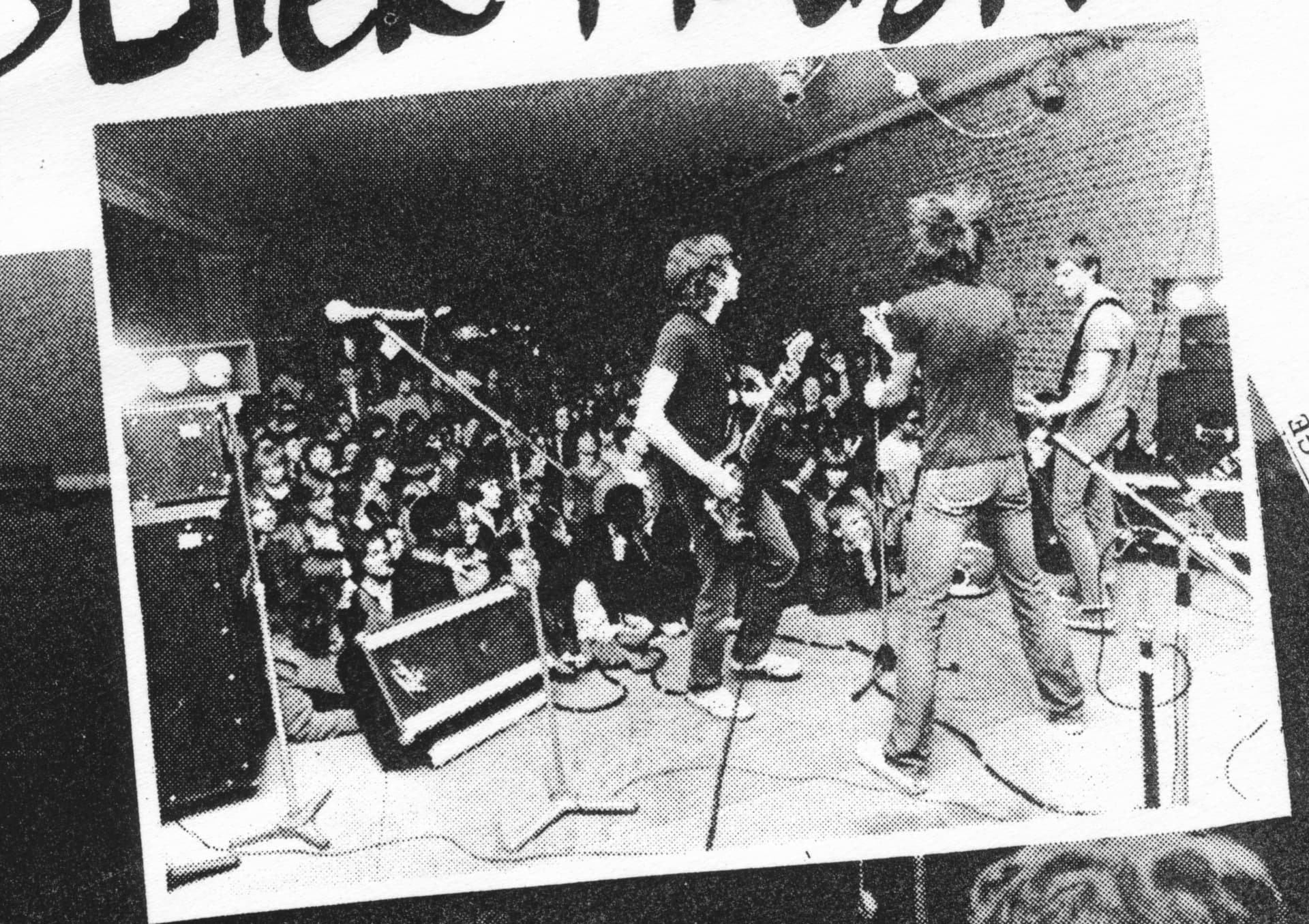 Band on stage in front of a packed crowd, halftone photocopy from a fanzine